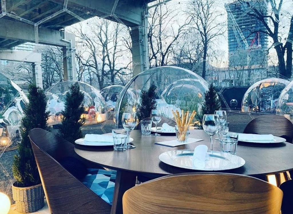 Outdoor dining domes with modern seating and white plates set for dinner
